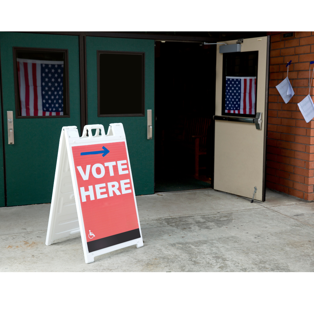 Polling place entrance with sign that reads 'Vote Here'. 