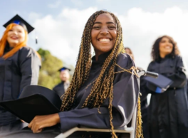 A graduate smiles at the camera from her wheelchair with her cap and gown